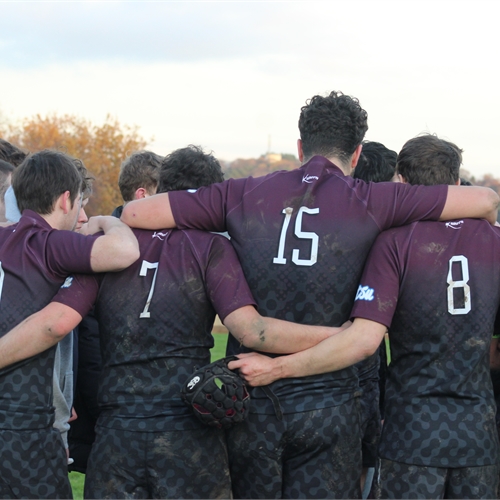 Image of a team interlocked with one another in a huddle, wearing sport attire with their numbers shown on their shirts.
