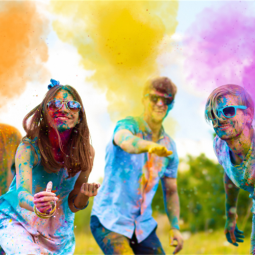 Image of students, surrounded by coloured smoke and covered in various colours.
